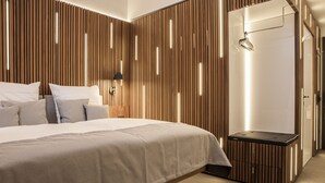 Un dormitorio moderno con una cama grande, un panel de madera con listones y una mesita de noche pequeña.