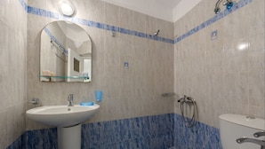 A bathroom with a sink, mirror, shower, and toilet. - Hotel Porto Carra (Santorini)