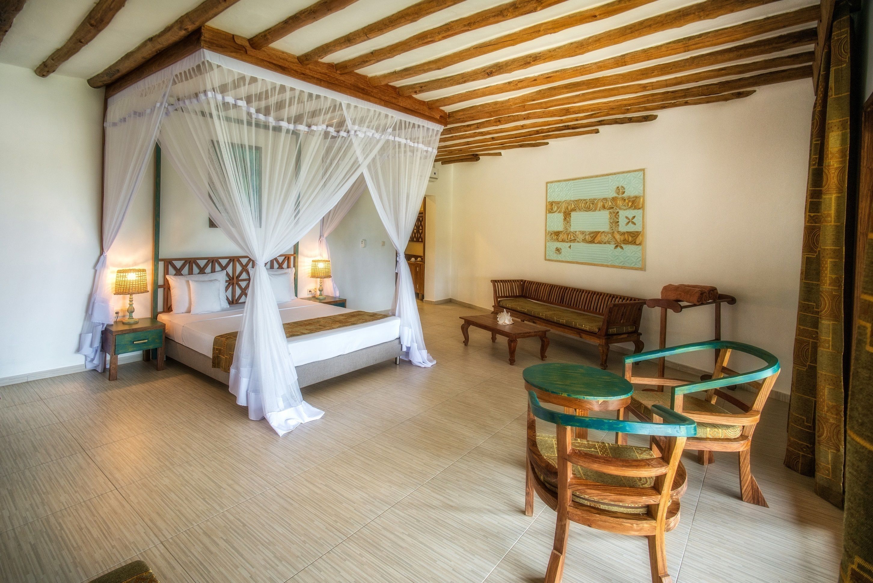 A bedroom with a four-poster bed, a wooden bench, and a round table with chairs.