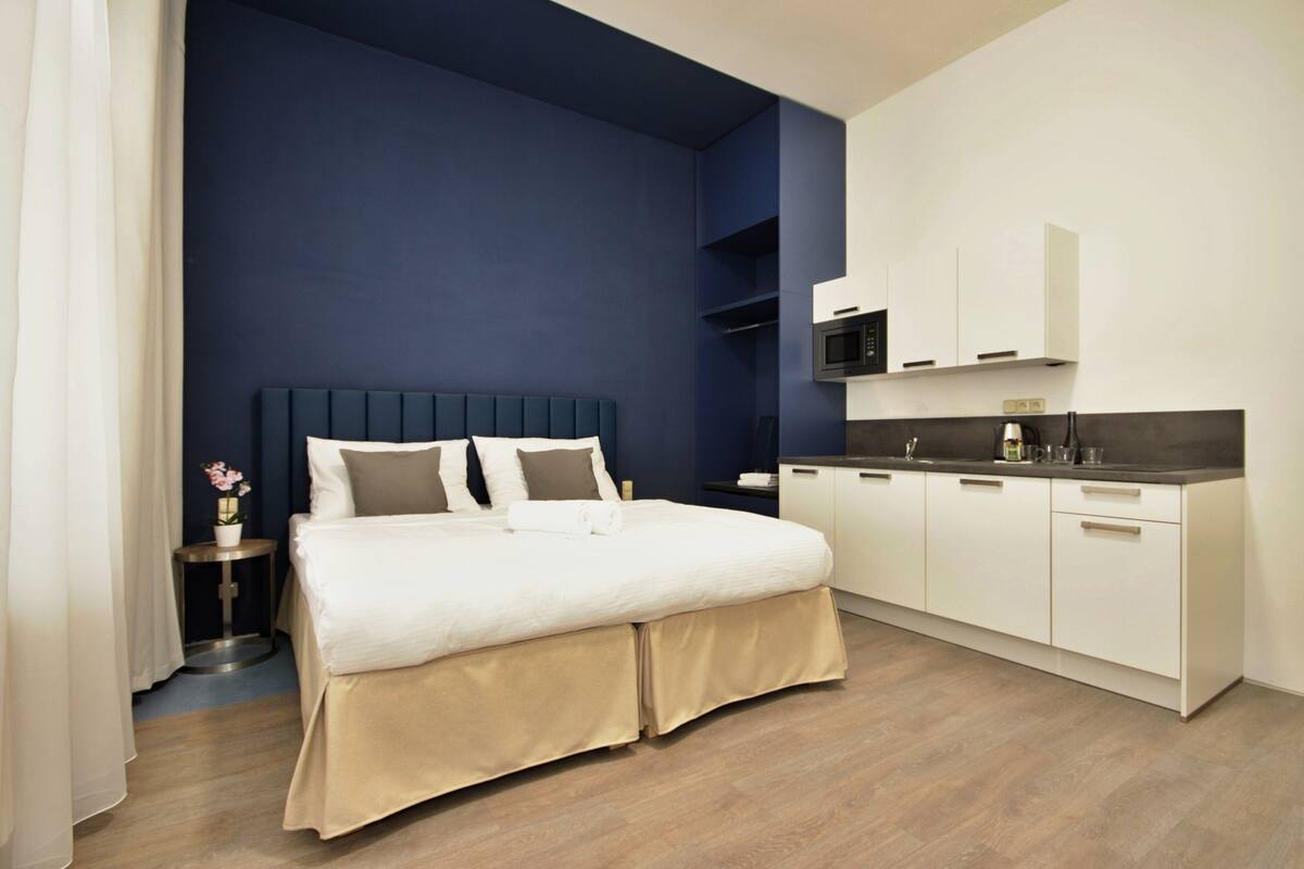 Una habitación de hotel moderna con una cama grande, un escritorio integrado y una kitchenette.