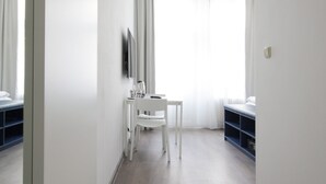 Een moderne hotelkamer met een groot raam, een bureau met stoel en een kledingkast.