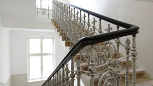 Een trap met versierde metalen leuningen en een handrail, die naar een bovenverdieping leidt.