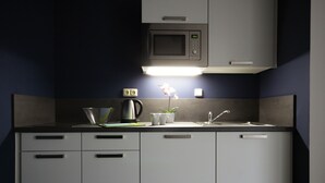 Een kleine keuken met een magnetron, spoelbak en kastjes.