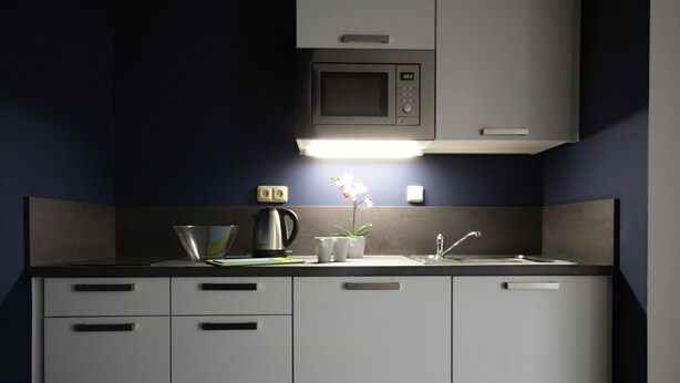 A compact kitchen with a microwave, sink, and cabinets. - Alveo Suites (Prague)