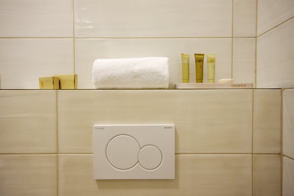 A bathroom with a towel, toiletries, and a thermostat.