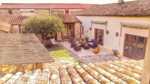 A courtyard with stone flooring, outdoor furniture, and a tree. - Il Borgo dell'Arcangelo (Tuili)
