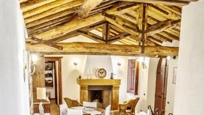 A dining area with a fireplace, wooden ceiling, and white furniture. - Il Borgo dell'Arcangelo (Tuili)