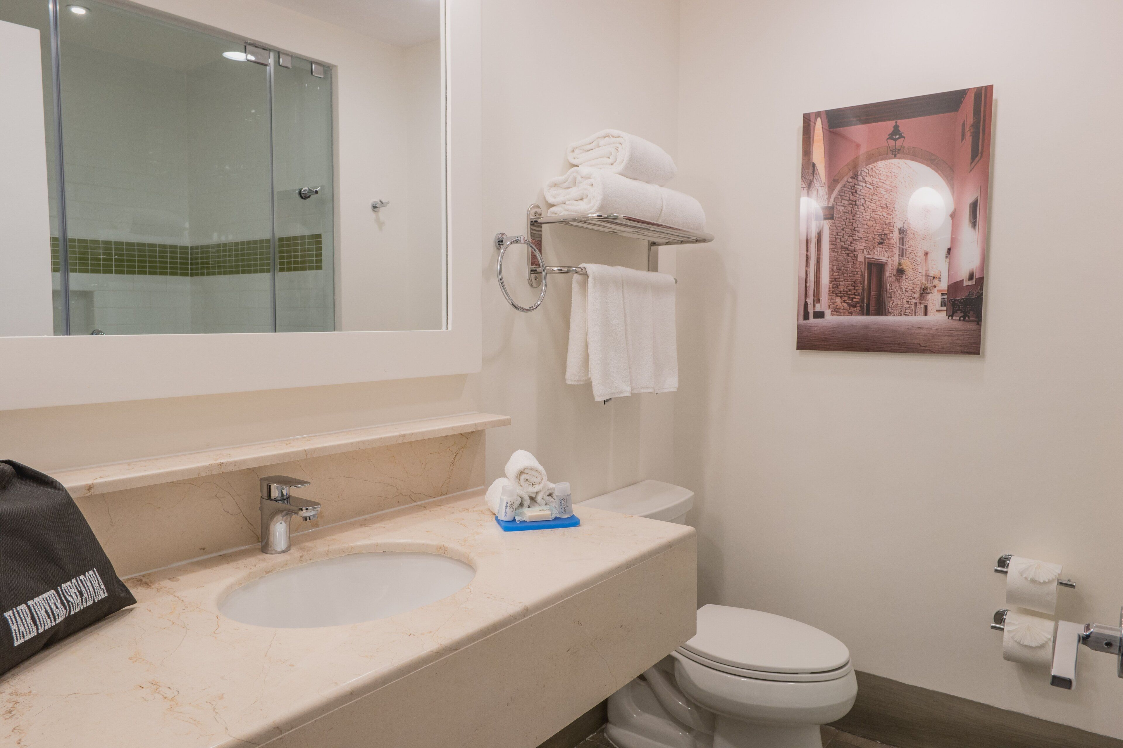 A bathroom with a sink, toilet, and a glass shower enclosure.
