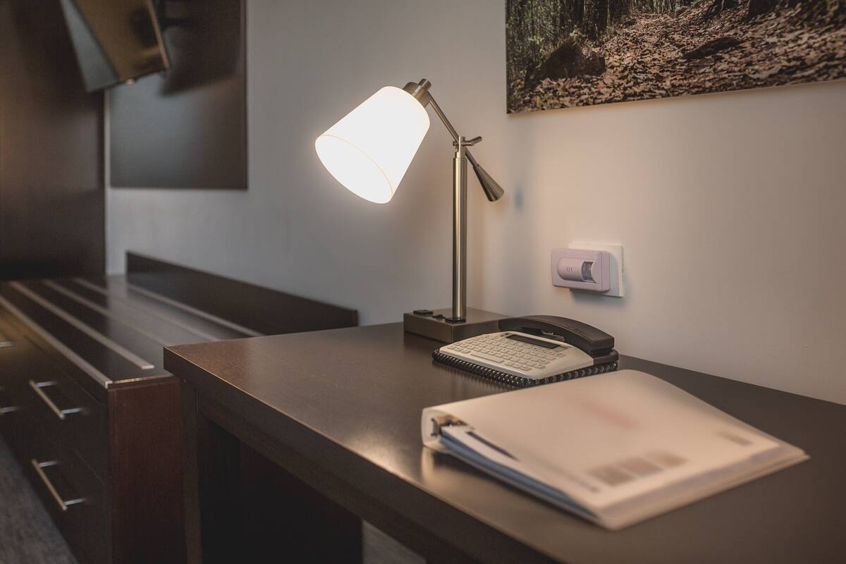 Een bureau met een lamp, telefoon, notitieboekje en een klembord.