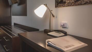 Un bureau avec une lampe, un téléphone, un bloc-notes et un presse-papiers.