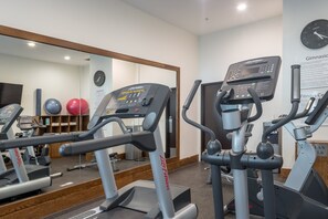 A gym with treadmills and exercise balls, a clock, and a sign about gymnasium.