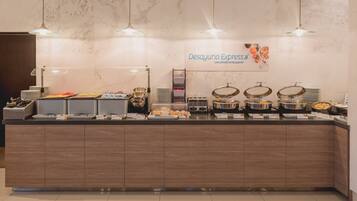 Un banco buffet con diversi cibi e un cartello che recita 'Desayuno Express'.