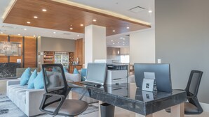 Un espace de bureau moderne avec une table en verre, plusieurs chaises, un ordinateur portable et une imprimante.