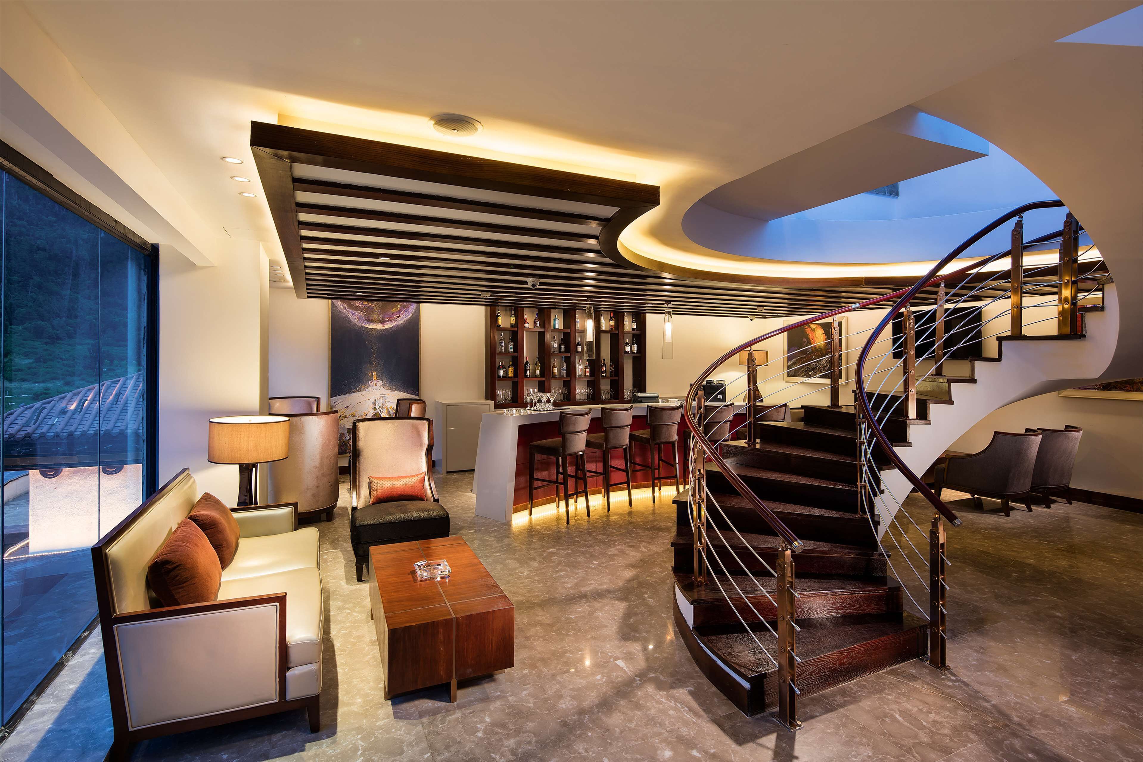 Un intérieur moderne avec un escalier à volutes, un espace bar et différents coins salon.