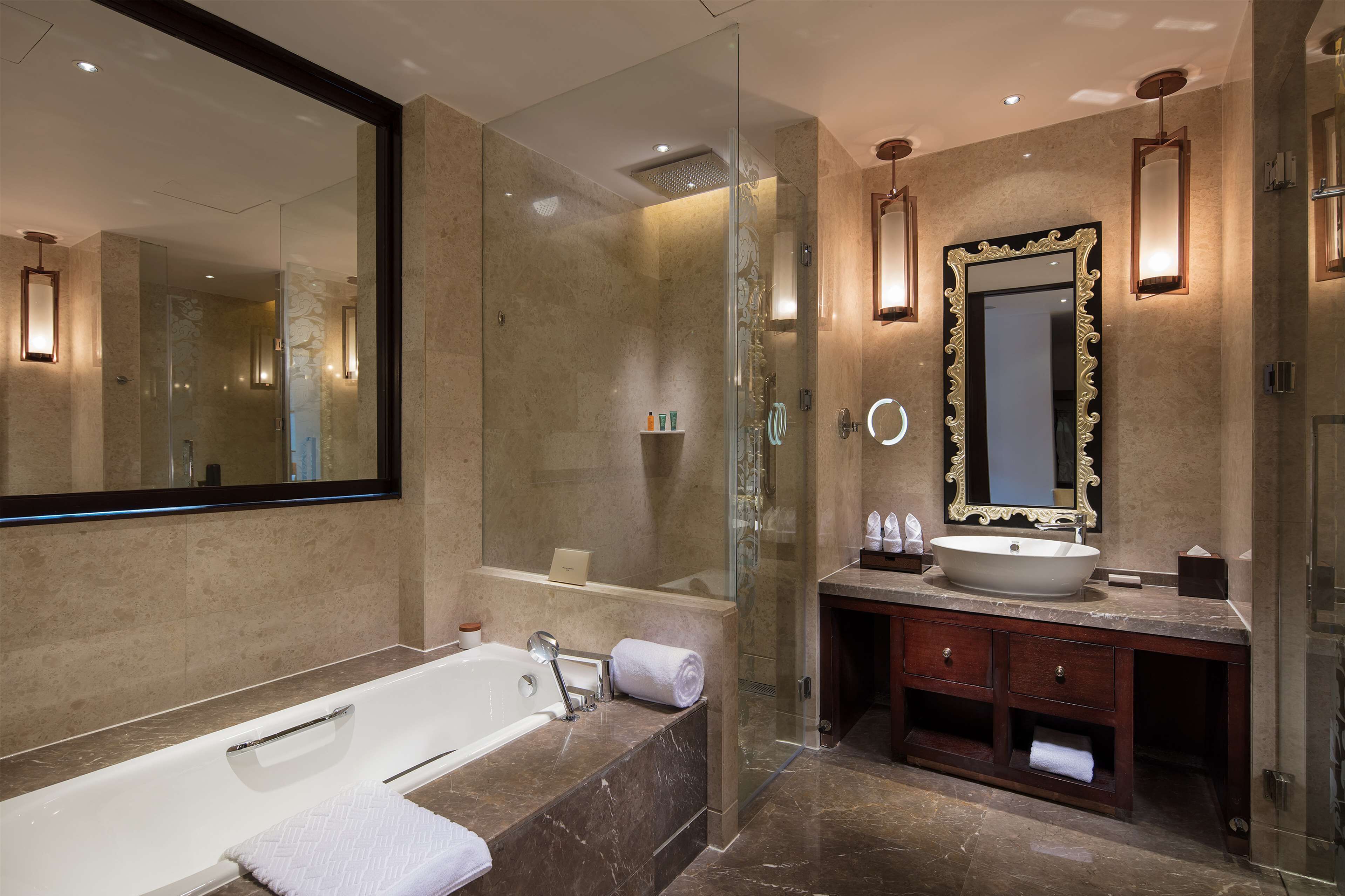 A modern bathroom with a large mirror, a bathtub, a vanity with a sink, and a shower area.