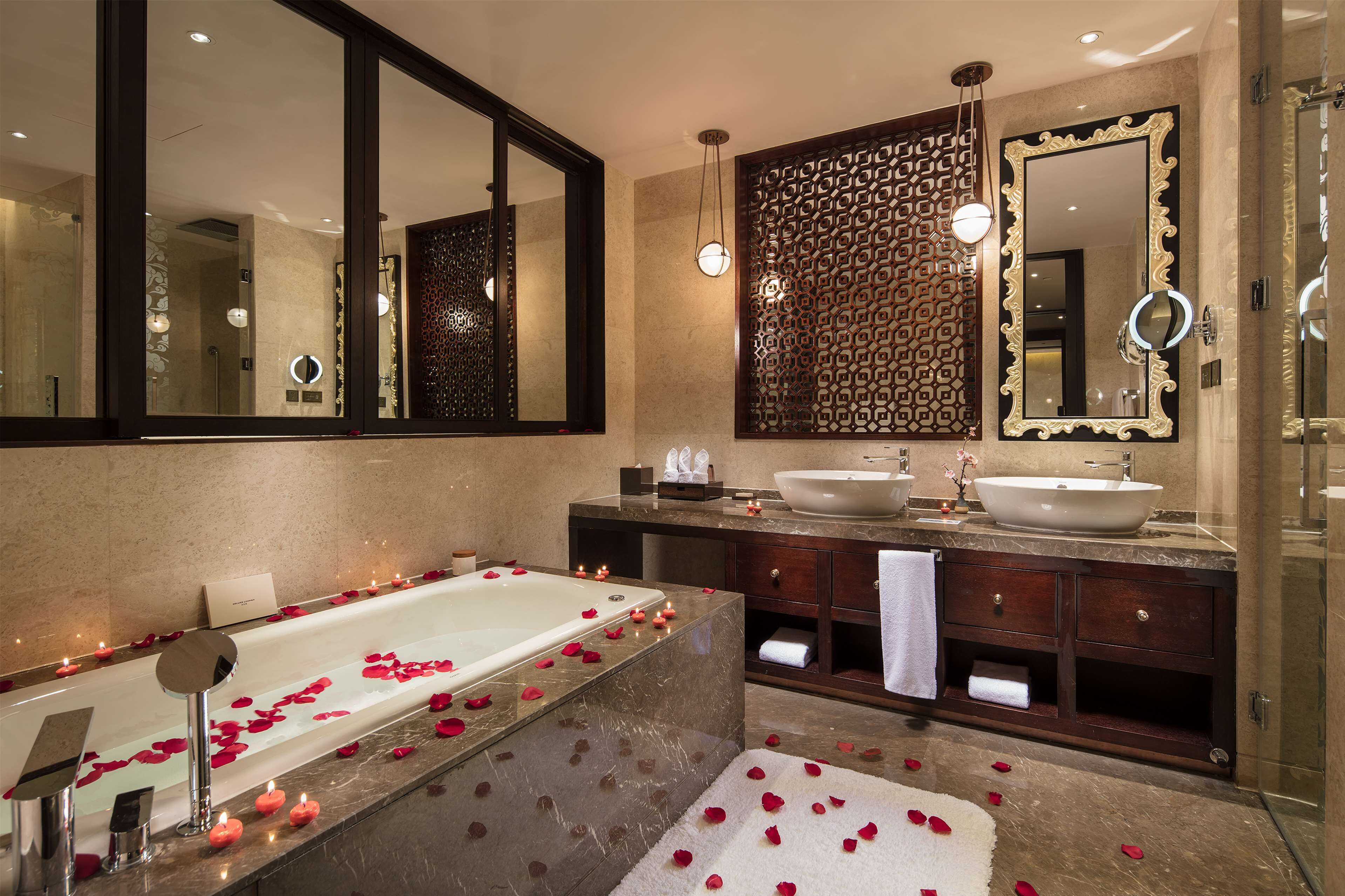 A modern bathroom with a large bathtub, two sinks, and a walk-in shower.