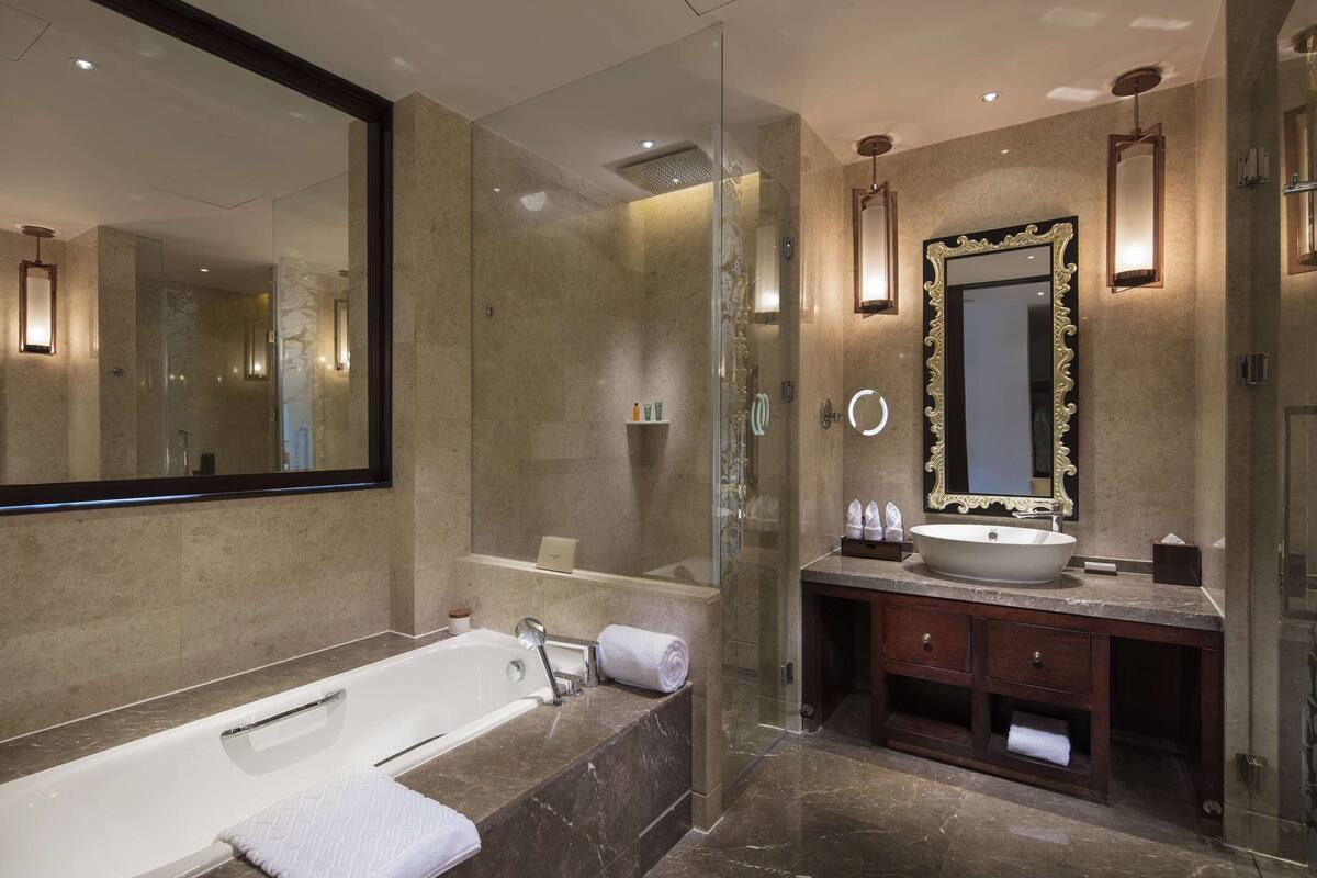 A modern bathroom with a glass-enclosed shower, a freestanding bathtub, and a vanity with a large mirror and sink.