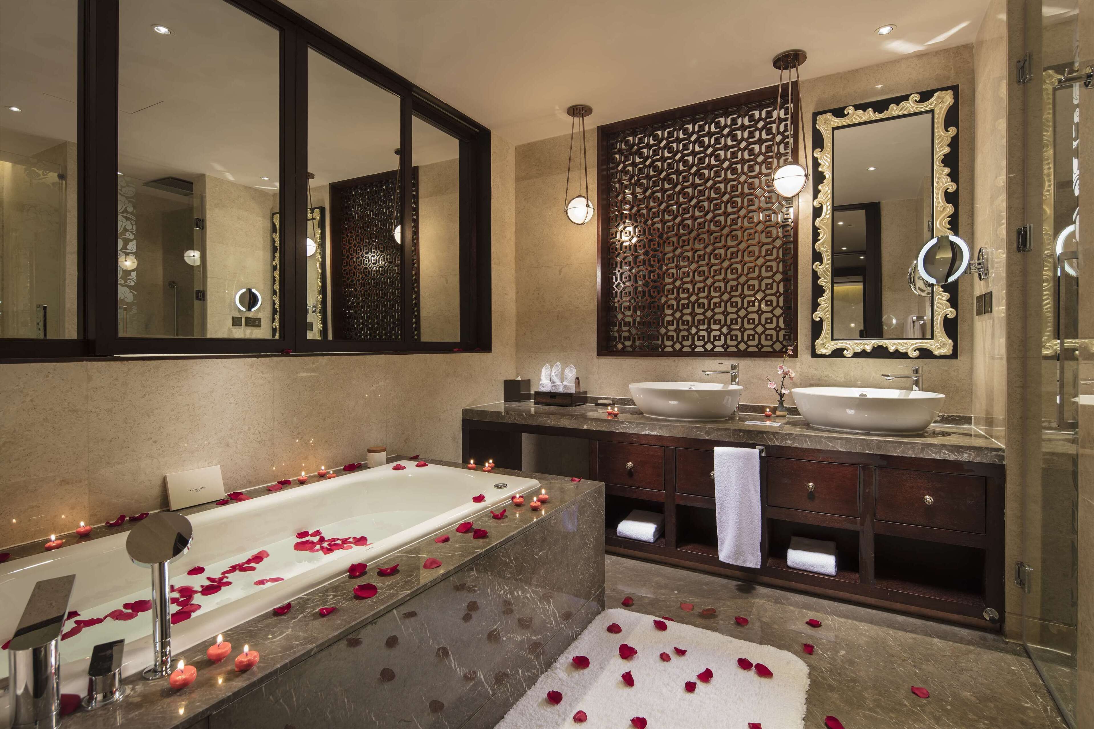 A modern bathroom with a large bathtub, two sinks, and a large mirror.