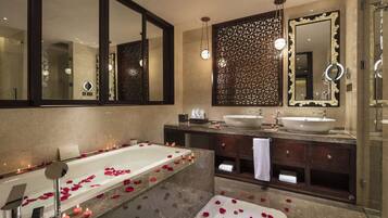 A modern bathroom with a large bathtub, two sinks, and a large mirror.