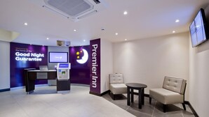 Zona de recepció d'hotel amb un taulell d'entrada, una quiosc digital i dues zones d'espera.