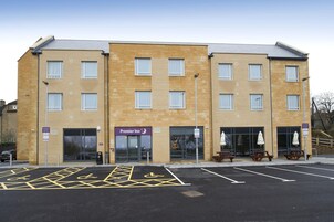 Un hotel de varios pisos con fachada de ladrillo, un cartel de Premier Inn y un estacionamiento con plazas para discapacitados.