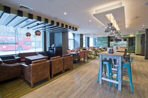 A modern restaurant with wooden flooring, a variety of seating including booths and tables, and large windows allowing natural light. - Premier Inn London Clapham (London)