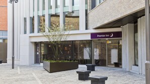 L’entrée d’un hôtel Premier Inn, avec un design moderne, un espace extérieur aménagé pour s’asseoir et une façade en briques.