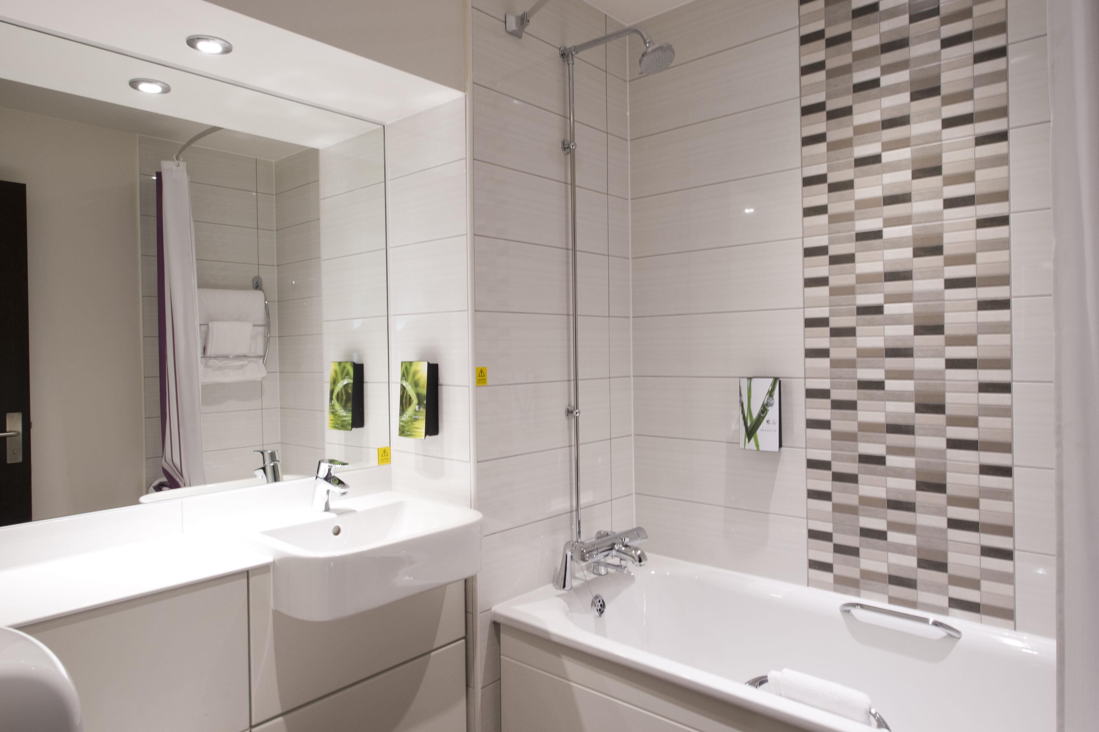 Ein modernes Badezimmer mit großem Spiegel, zwei Waschbecken, einer Badewanne und einer Dusche.
