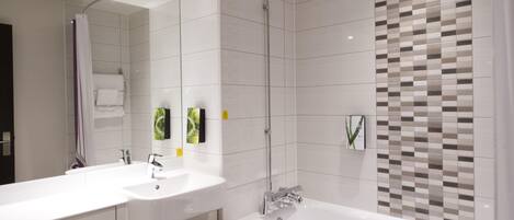 Une salle de bain moderne avec un grand miroir, deux lavabos, une baignoire et une douche.
