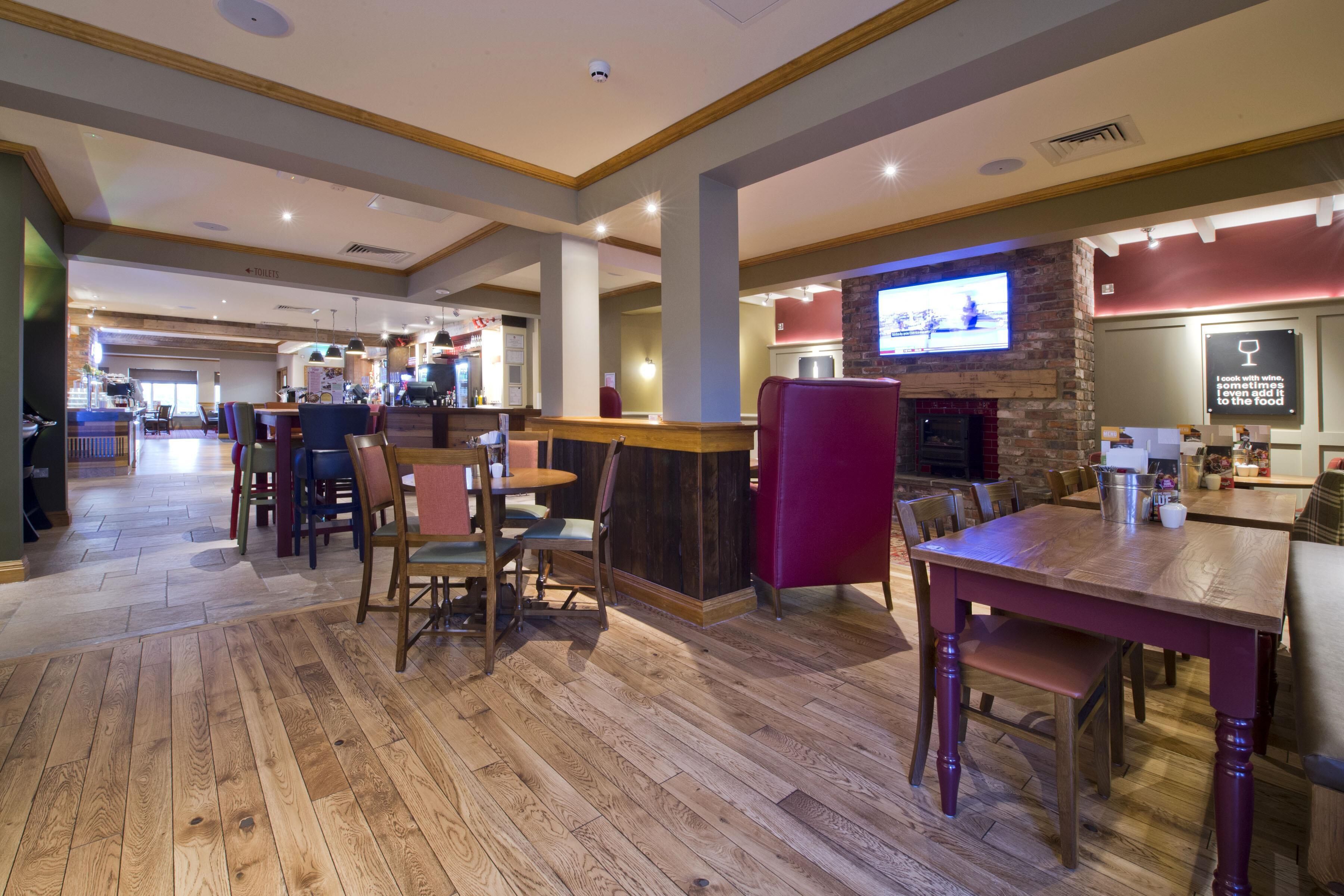 A restaurant with wooden flooring, a bar area, and a television screen.