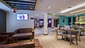 Un hall d’hôtel avec des canapés en cuir, un coin bar et une enseigne « Premier Inn ».