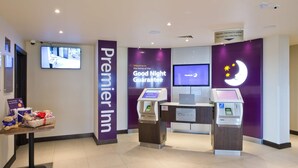 A Premier Inn reception area with a check-in counter, a television mounted on the wall, and a sign indicating a fast-track key collection point. - Premier Inn Thirsk (Thirsk)