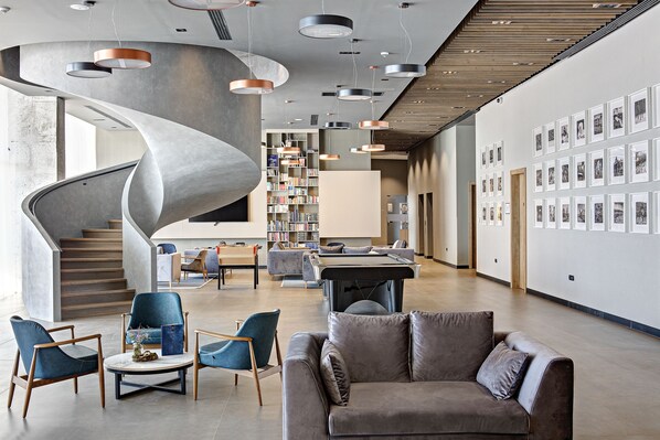 Un interior moderno con una escalera de caracol, una biblioteca y una pared de cuadros enmarcados.