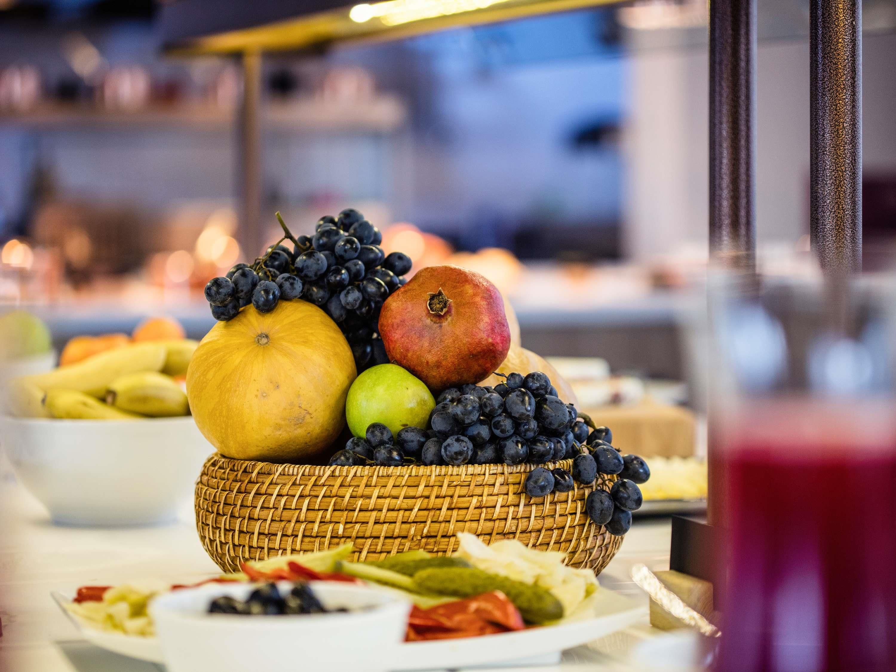 A fruit basket with a variety of fruits including grapes, a pomegranate, and a pumpkin.