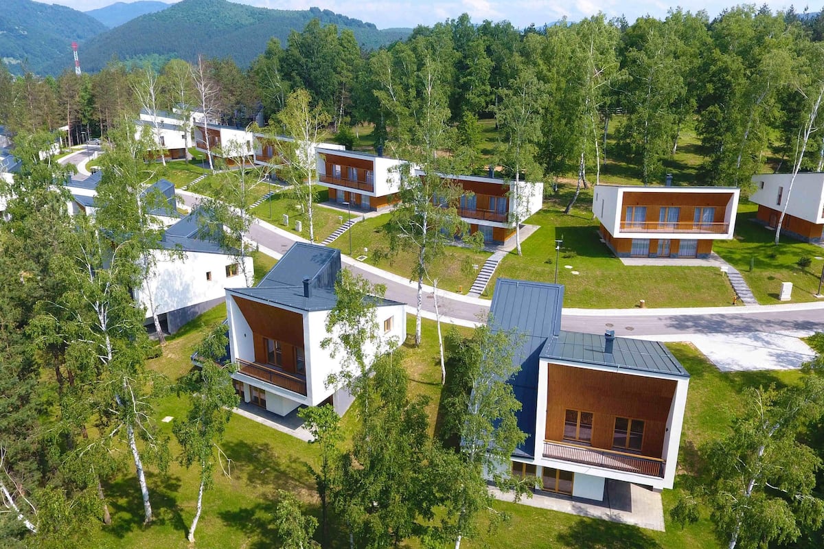 Zona residencial con casas modernas, rodeada de árboles y colinas.