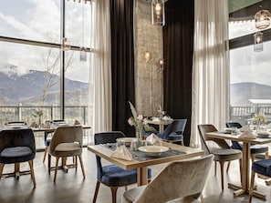 Ein Restaurant mit großen Fenstern, Bergblick und modernen Möbeln.