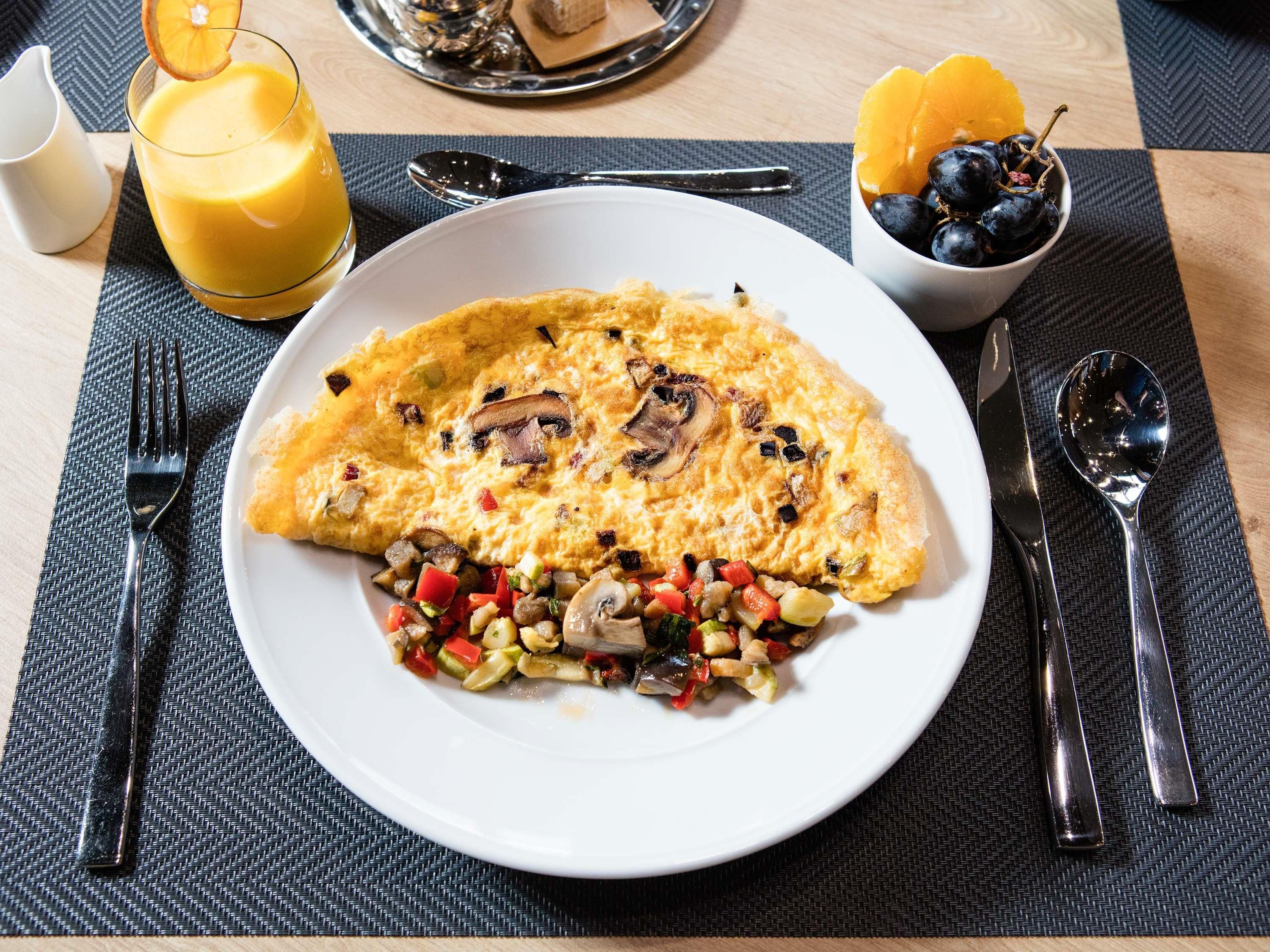 Ein Teller Frühstück mit Omelett, einem gemischten Salat und einem Glas Orangensaft.