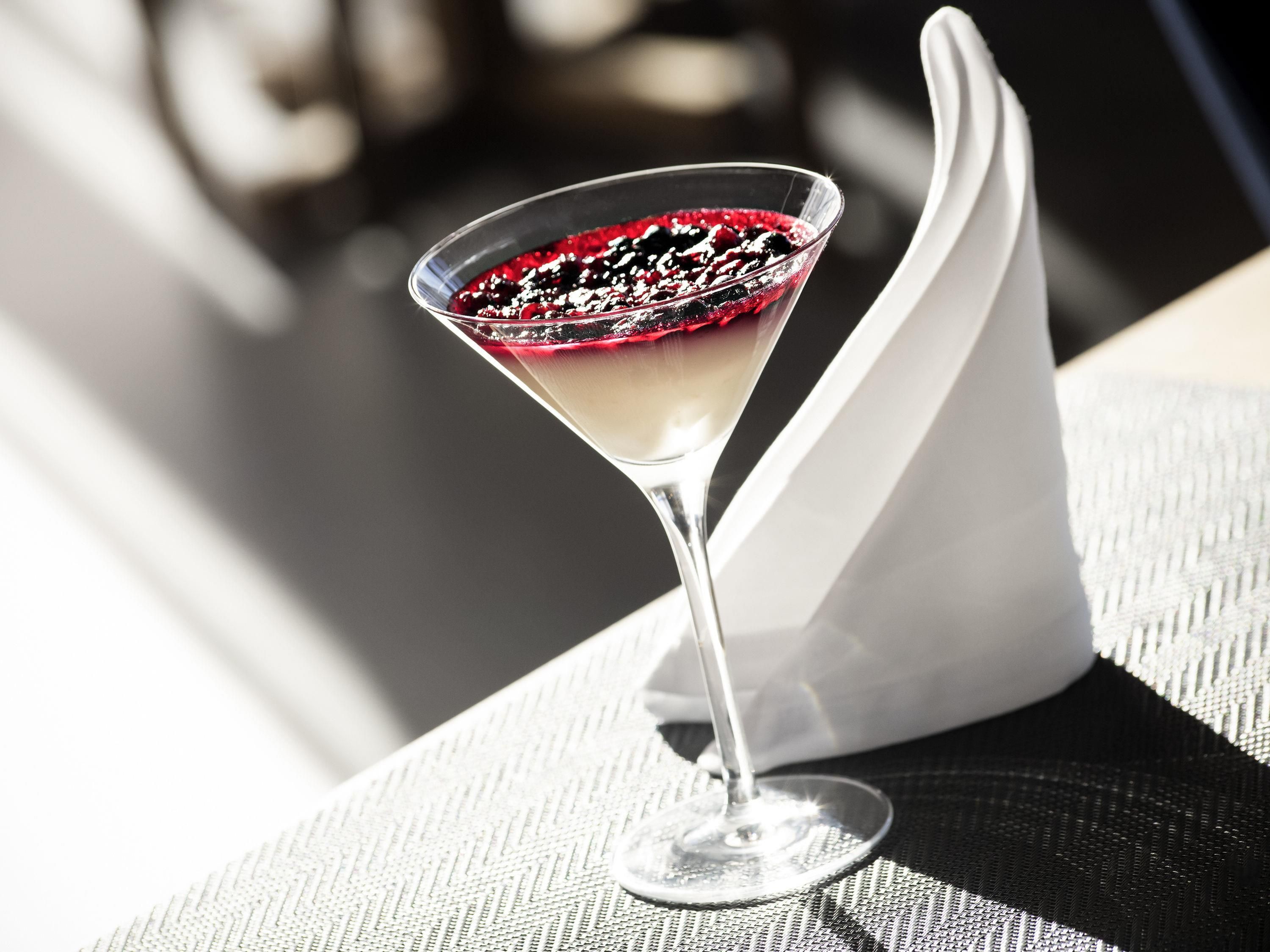 Una copa de martini con una baya roja como adorno sobre una superficie texturizada.