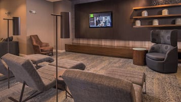 A modern lounge area with comfortable seating, a flat-screen TV, and decorative shelves.