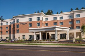 Un hotel Courtyard Marriott con fachada de ladrillo, múltiples ventanas y un área de entrada cubierta.