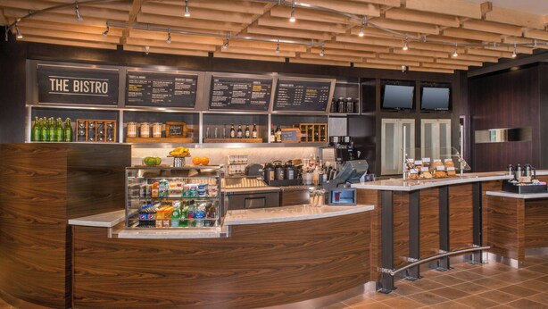A modern bistro with a curved counter, wooden ceiling, and a menu board.