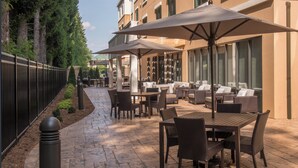 An outdoor patio with tables and chairs, umbrellas, and a stone pathway.
