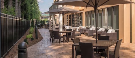 An outdoor patio with tables and chairs, umbrellas, and a stone pathway.