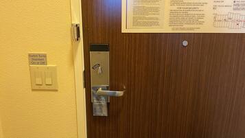 Puerta de una habitación de hotel con un letrero que indica la hora de salida y las instrucciones de seguridad para emergencias.