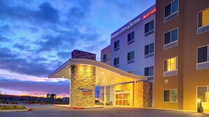 Un hotel Fairfield Inn & Suites Marriott con un acceso de fachada de piedra y un cielo despejado al fondo.