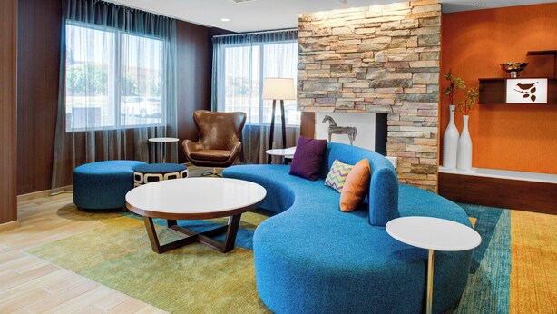 Una sala de estar moderna con un sofá seccional azul, una mesa redonda de centro, un sillón de cuero y una pared de acento de piedra.