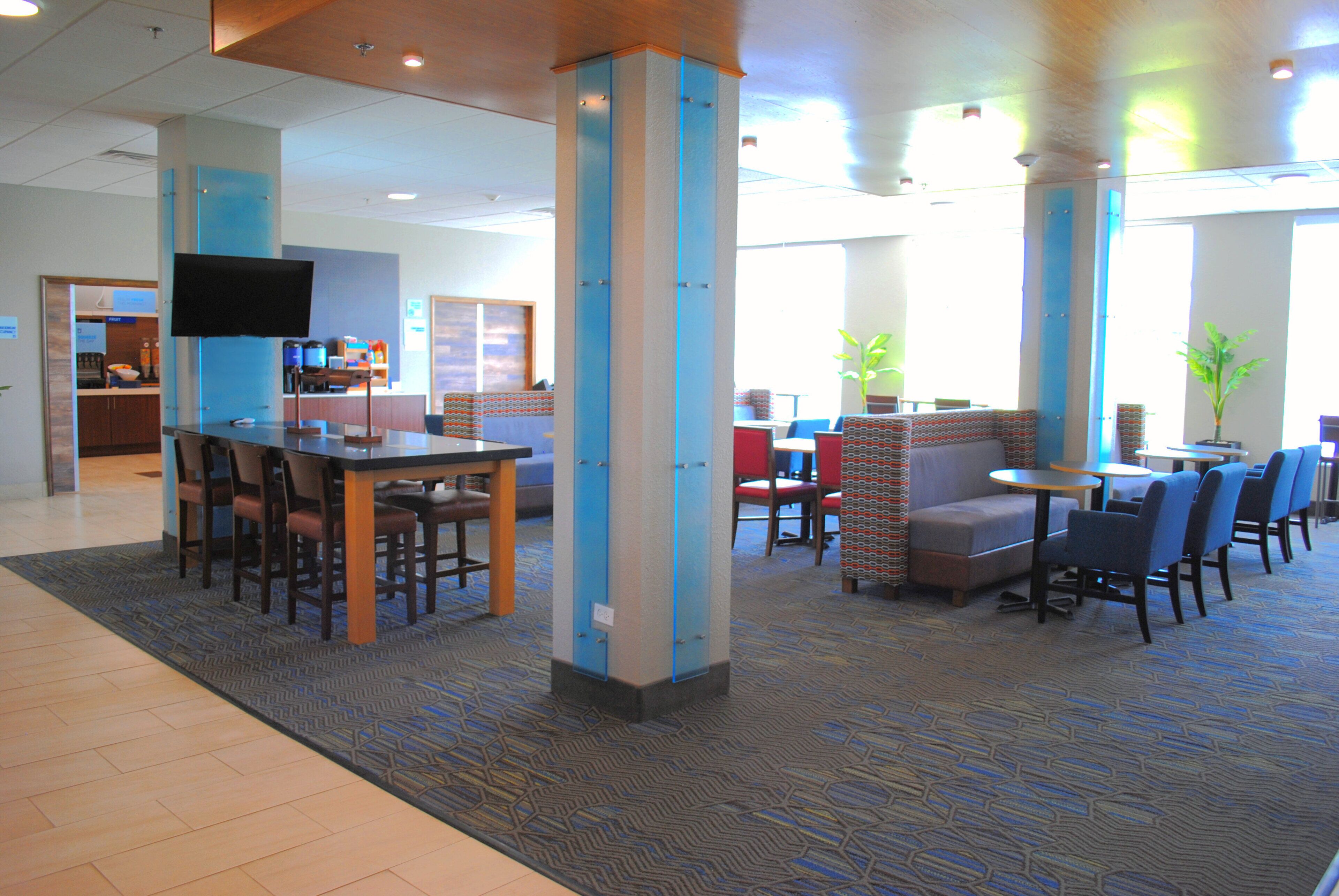 A hotel lobby with a reception desk, seating area, and a television.