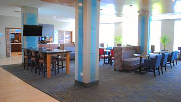 A hotel lobby with a reception desk, seating area, and a television.