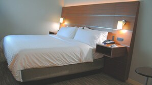 A hotel room with a large bed, two bedside tables with lamps, and a small round table.