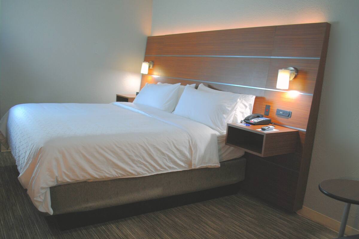 A hotel room with a large bed, two bedside tables with lamps, and a small round table.